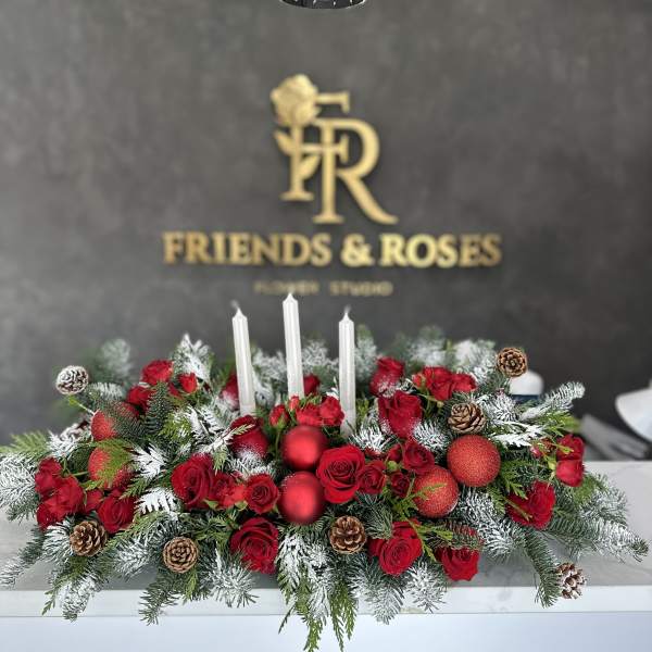 Red rose centerpiece with white candles, pinecones, and frosted evergreen