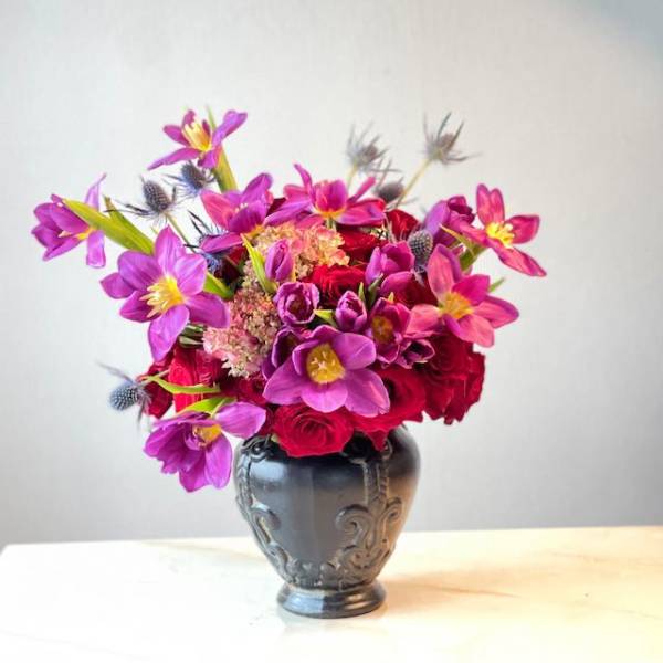 Bright pink and purple bouquet in a dark decorative vase