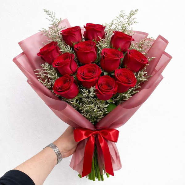 Bouquet of red roses wrapped in pink paper with a red ribbon