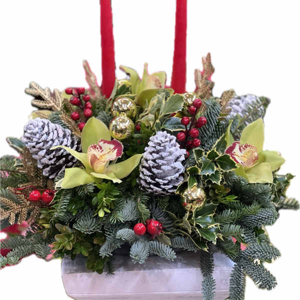 Holiday floral centerpiece with red candles, pinecones, and orchids in a white container