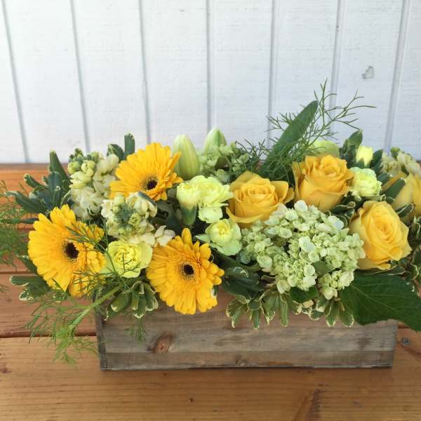 Low yellow flower arrangement with roses and gerbera daisies in a rustic wooden box