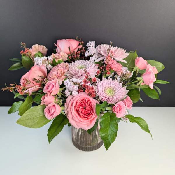 Pink roses and chrysanthemums arranged in a ribbed glass vase