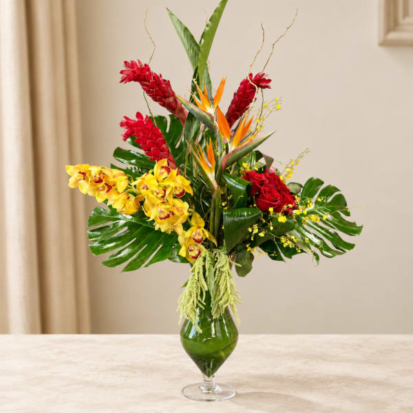 Tropical flower arrangement in a green glass vase