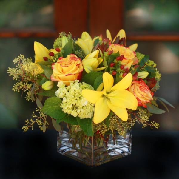 Yellow roses and lilies in a clear glass vase