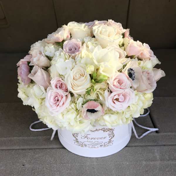 Round bouquet of pale pink and white roses in a white hatbox