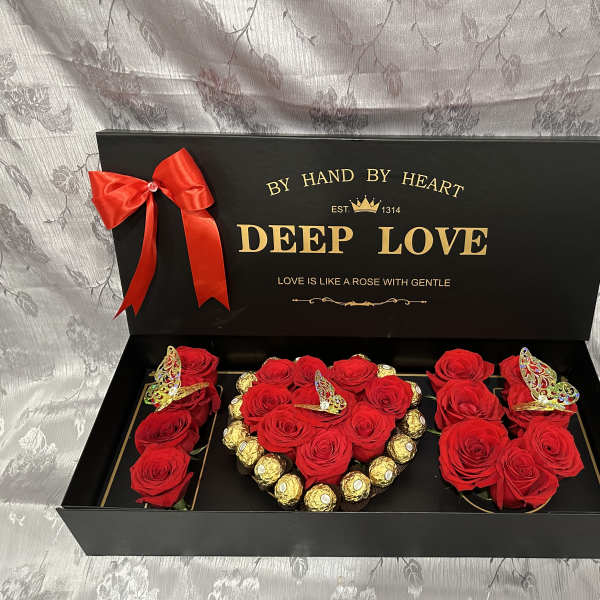 Black gift box with red roses, gold chocolates, and a red ribbon