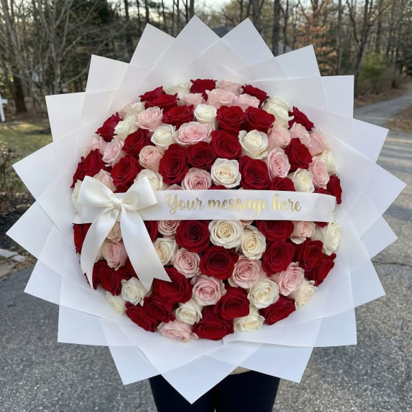 Large bouquet of red, pink, and white roses wrapped in white paper with a ribbon