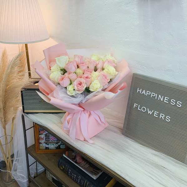 Pink and white rose bouquet wrapped in pastel paper with a ribbon