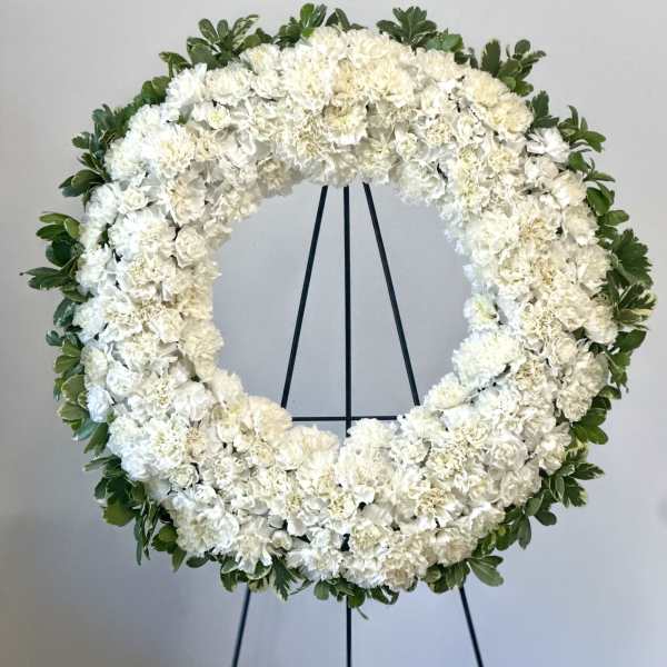 White floral wreath on a black stand