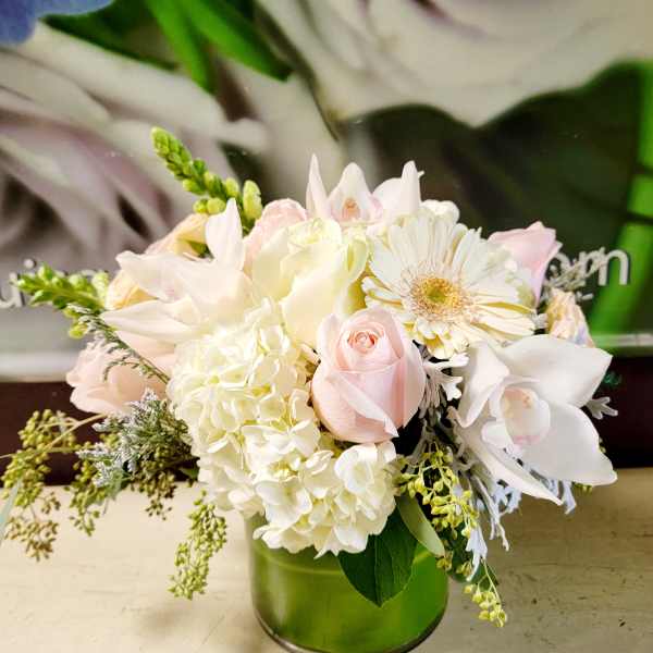 Soft pink and white bouquet in a green glass vase