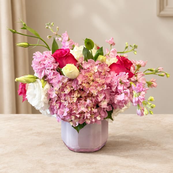 Pink and white floral arrangement in a lavender vase