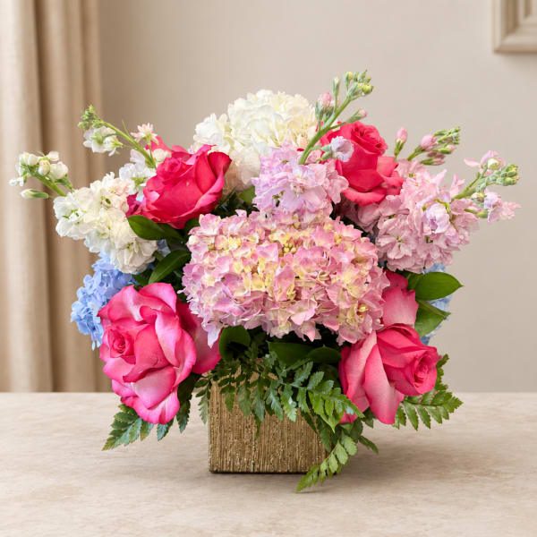 Pink roses and pastel hydrangeas arranged in a gold vase