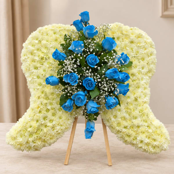 Heart-shaped floral wreath with blue roses and pale yellow chrysanthemums on a stand