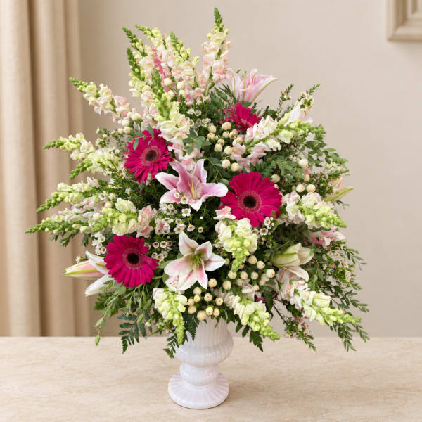 Pink and white mixed flower arrangement in a white pedestal vase