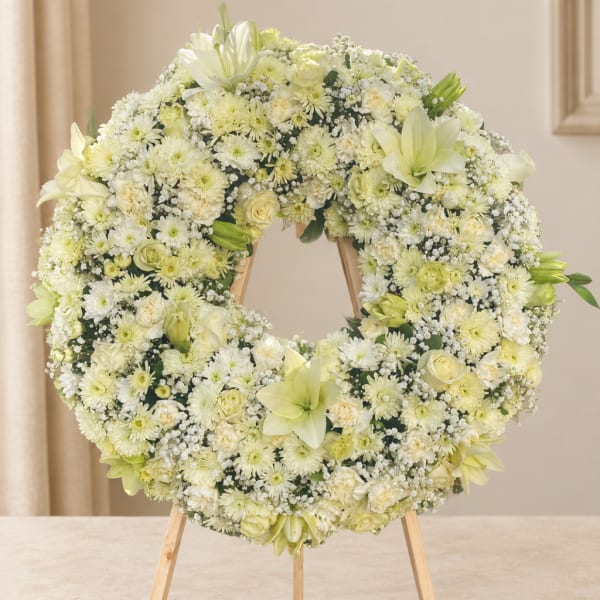 White and pale yellow floral wreath on a wooden stand