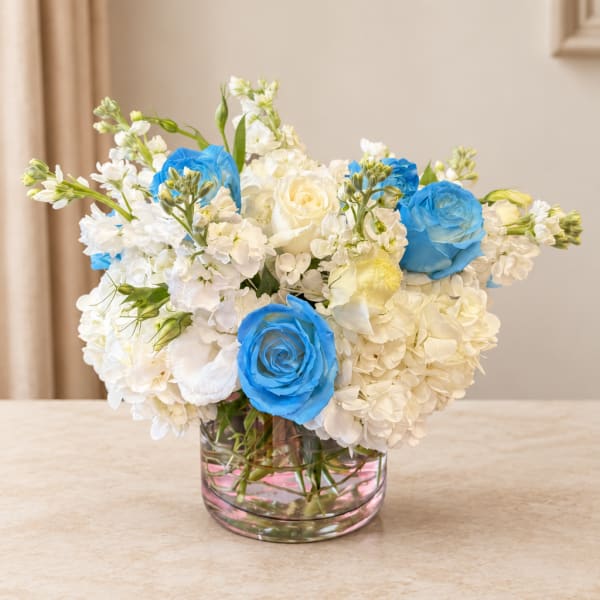 White and blue flower arrangement in a clear glass vase