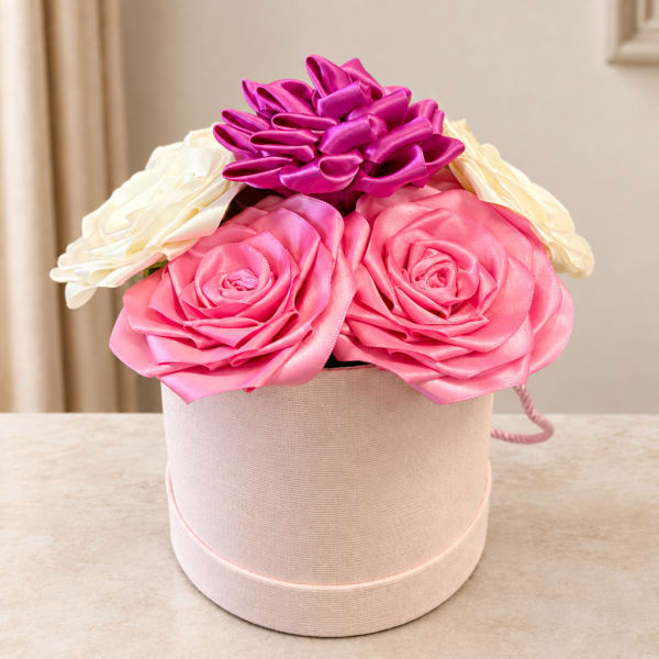 Pink and white ribbon roses arranged in a round hatbox