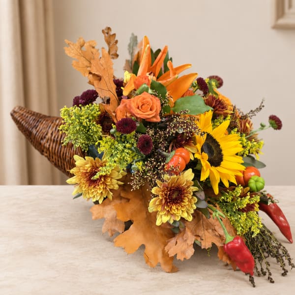 Autumn bouquet with sunflowers, roses, and orange lilies in a wicker cornucopia