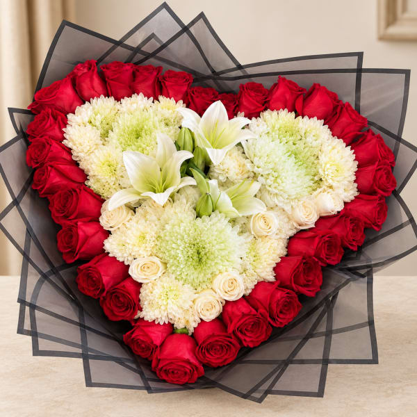 Heart-shaped bouquet of red roses, white lilies, and pale chrysanthemums wrapped in black paper