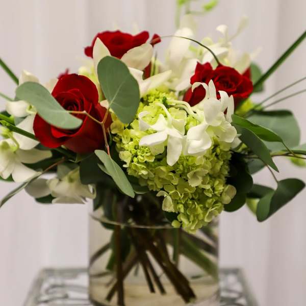 Red roses and white flowers arranged in a clear glass vase