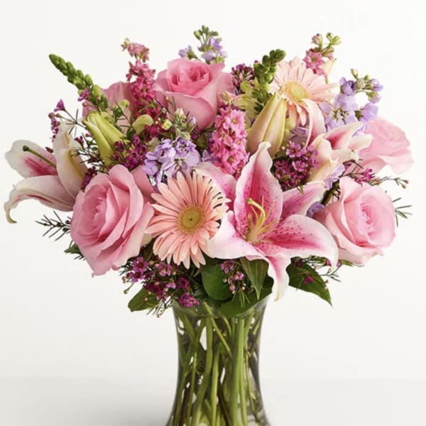 Pink roses and lilies arranged in a clear glass vase