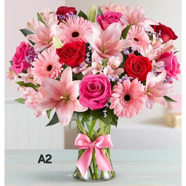 Pink and red mixed bouquet in a clear glass vase with a pink ribbon