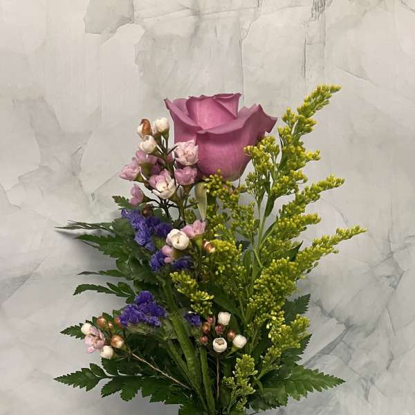 Pink rose bouquet in a clear glass vase with small purple and white flowers