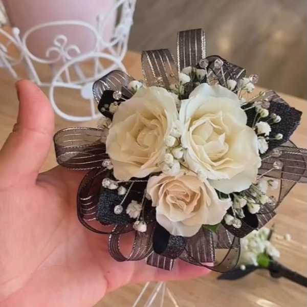 Small cream rose bouquet with dark ribbon loops and baby's breath