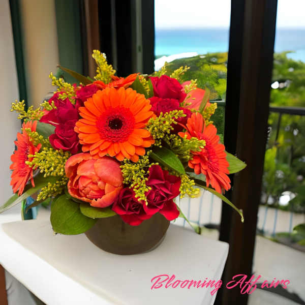 Orange gerbera daisies and red roses in a round vase
