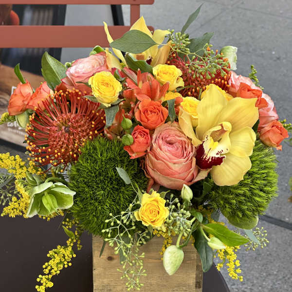 Colorful floral arrangement in a wooden box with roses and orchids