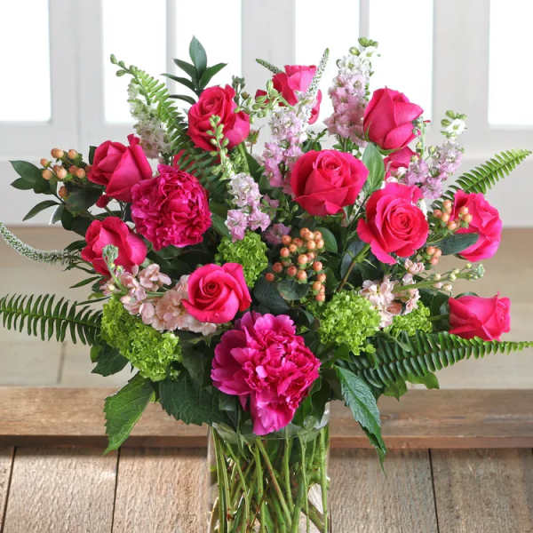 Pink roses and carnations arranged in a clear glass vase