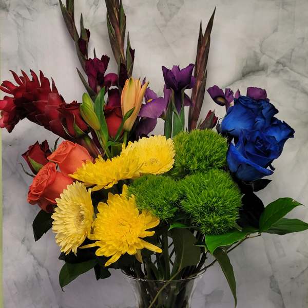 Colorful mixed bouquet in a clear glass vase with roses, chrysanthemums, and lilies