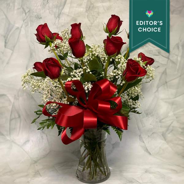 Red roses in a clear glass vase with a large red ribbon