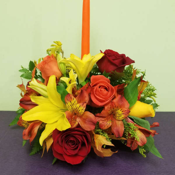 Red and yellow floral arrangement with a tall orange candle