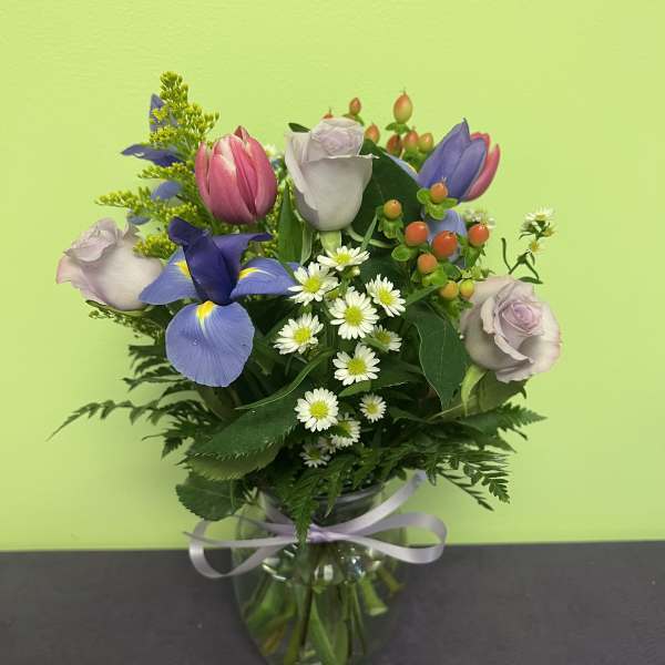 Mixed bouquet of roses, tulips, and daisies in a glass vase