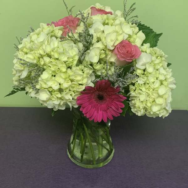 Pink and white flowers arranged in a glass vase