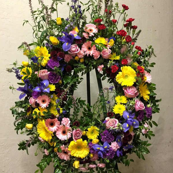Colorful floral wreath on a stand with roses, gerbera daisies, and irises