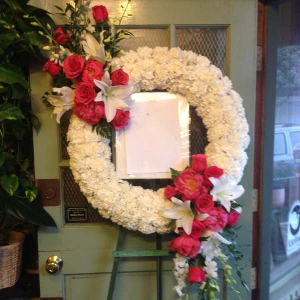 White floral wreath with pink roses and lilies on an easel