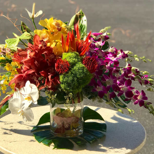Colorful tropical flower arrangement in a clear glass vase