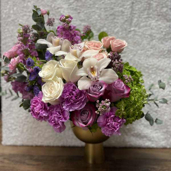 Pink and white floral arrangement in a gold vase