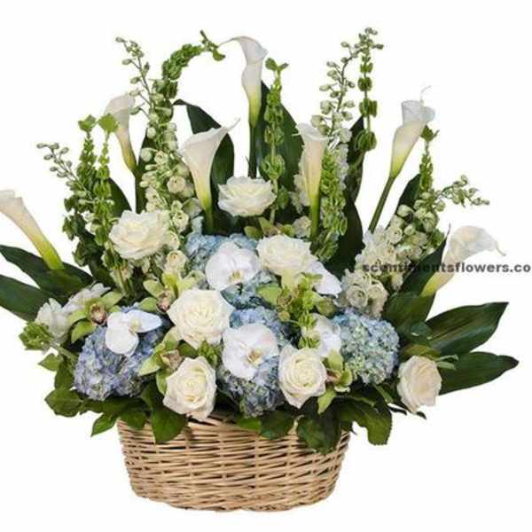 Tall white and blue flower arrangement with calla lilies and roses in a woven basket