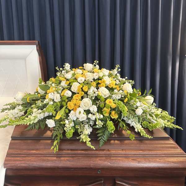 White and yellow floral spray on a casket