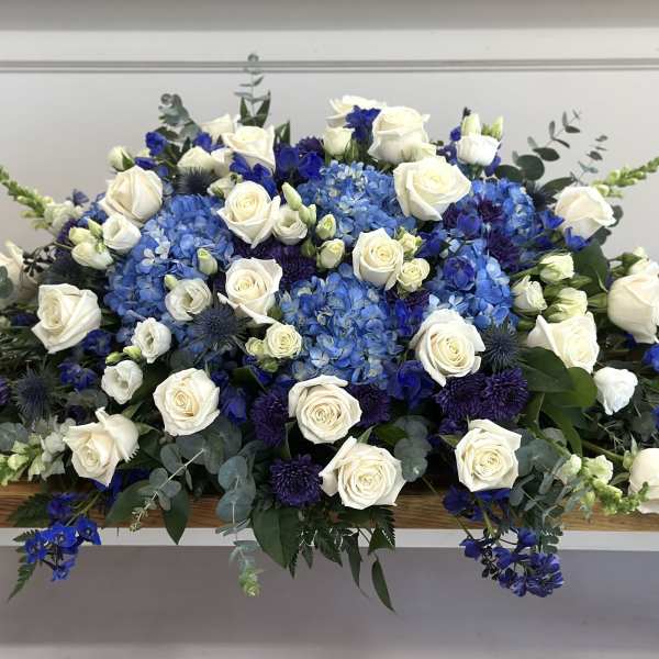 Blue and white floral arrangement with roses and hydrangeas on a table