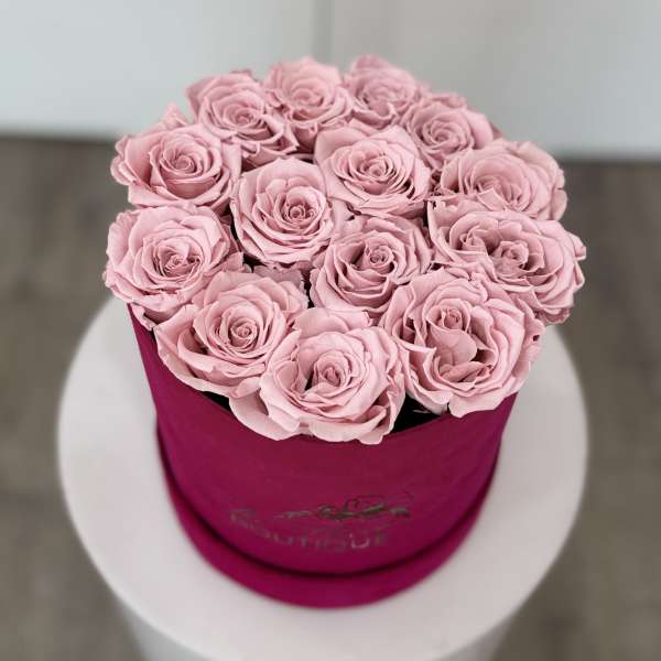 Pink roses arranged in a round magenta box