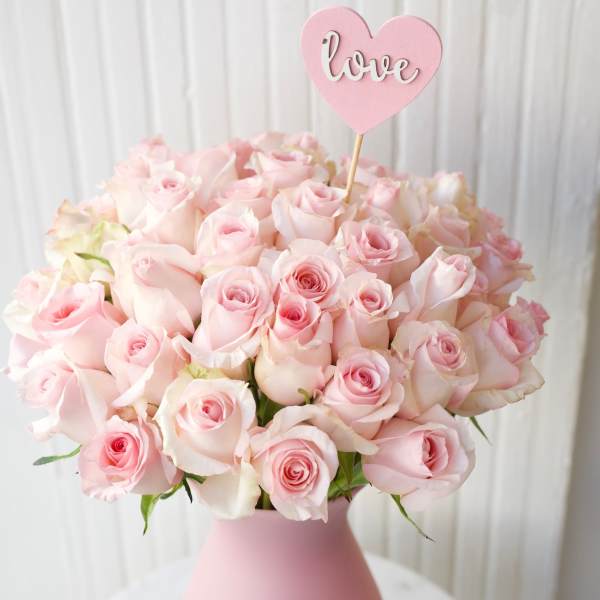 Pink rose bouquet in a matte pink vase with a heart-shaped love pick