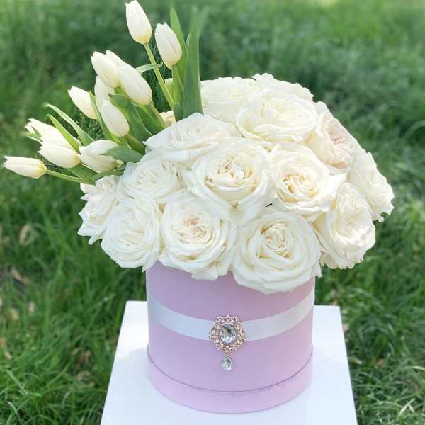 White roses and tulips arranged in a pink hat box