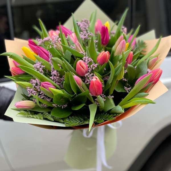 Bouquet of pink and yellow tulips with purple filler flowers