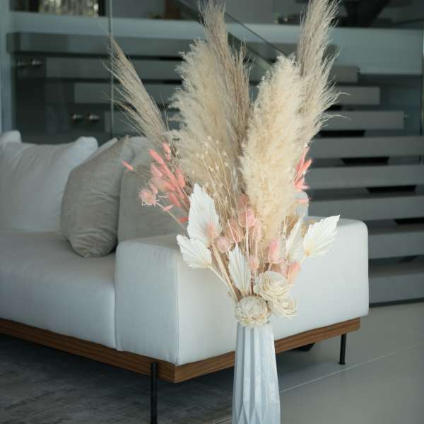 Tall dried floral arrangement in a white vase with beige and pink accents