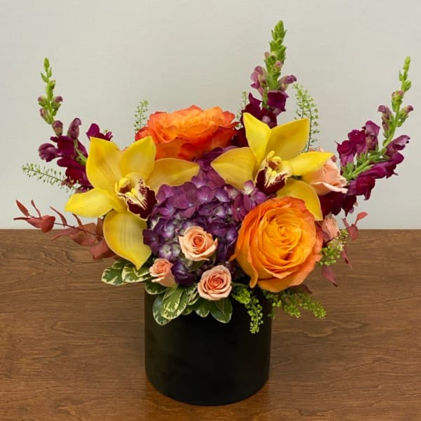 Orange roses and yellow orchids in a black vase with purple blooms
