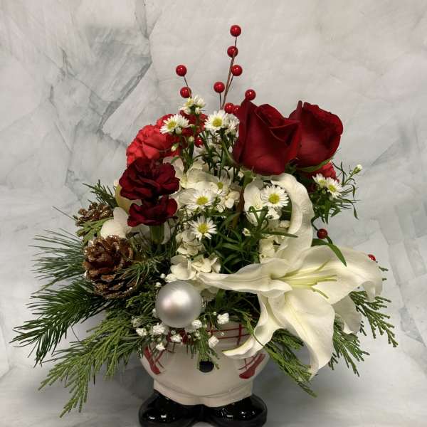Holiday floral arrangement in a Santa-shaped container with red roses and white lilies